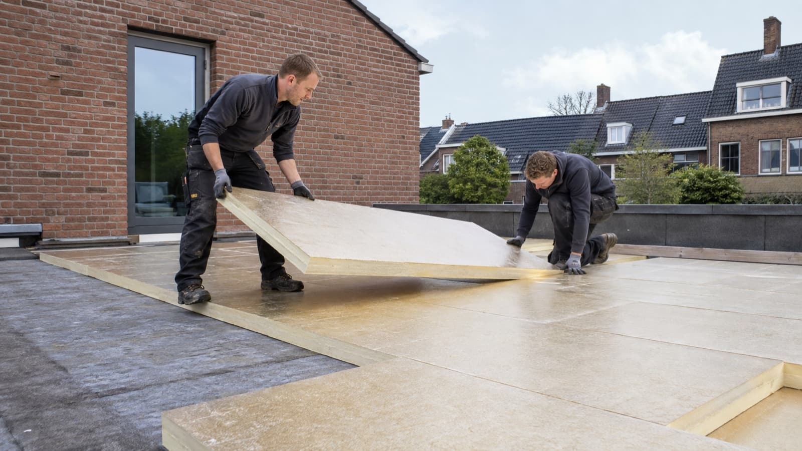 Dakdekkers plaatsen isolatieplaten op een plat dak
